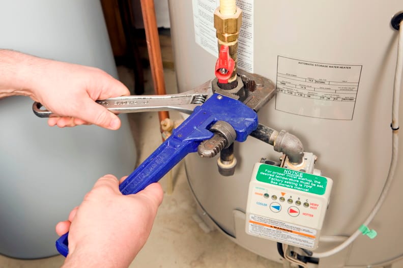 Plumber repairing water heater pipe connection in Peachtree Corners, Georgia home