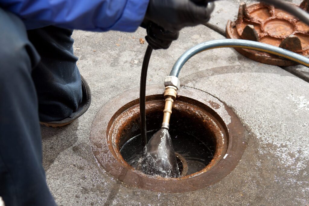 Plumber hydro jetting a sewer line through a manhole in Peachtree Corners